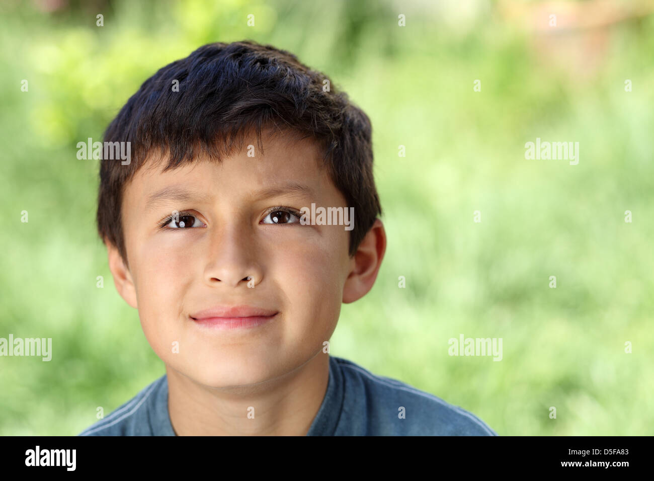 Young boy outside looking up with natural green background - copy space to right Stock Photo