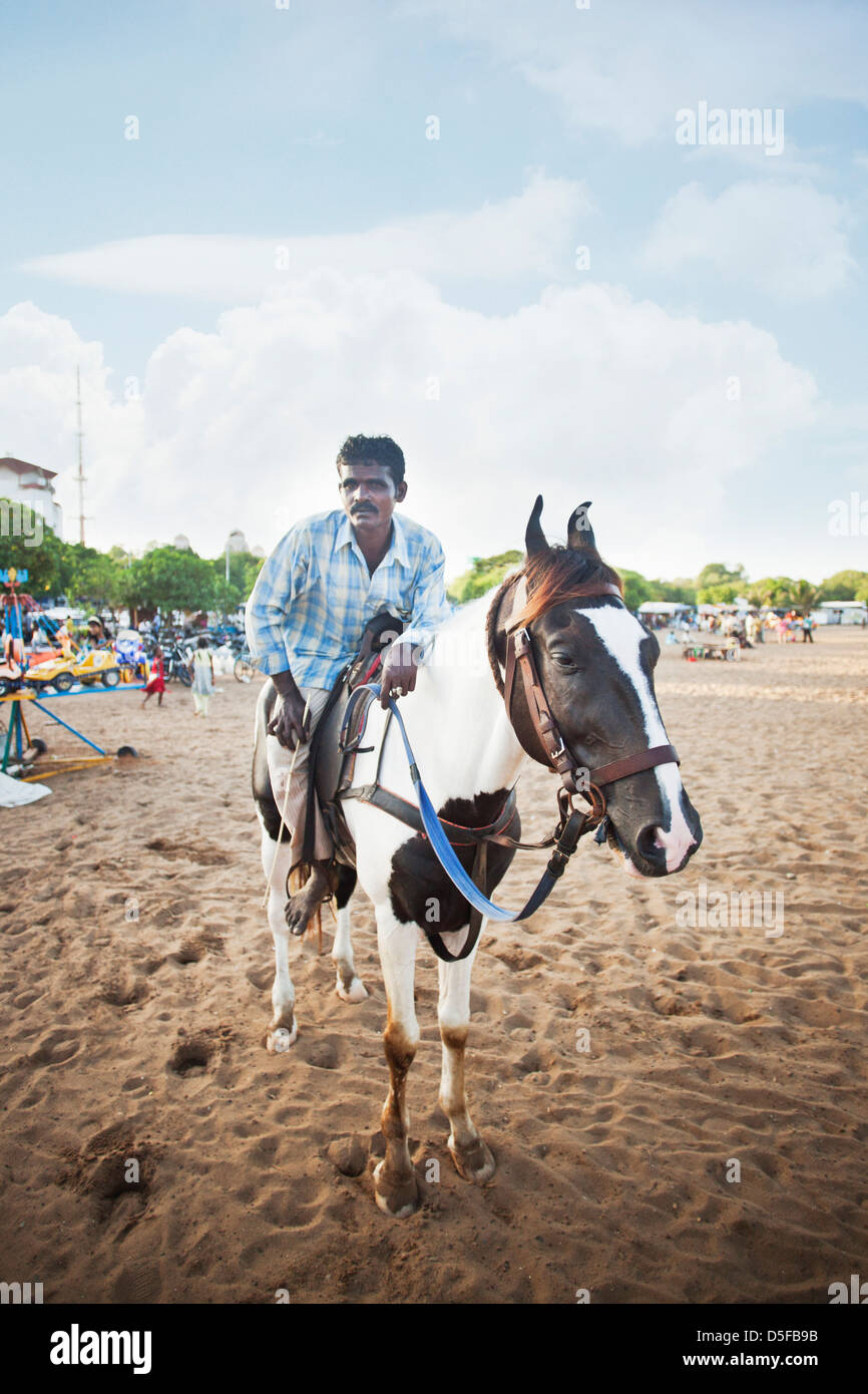 Person enjoying horseback riding on the beach, Chennai, Tamil Nadu, India Stock Photo
