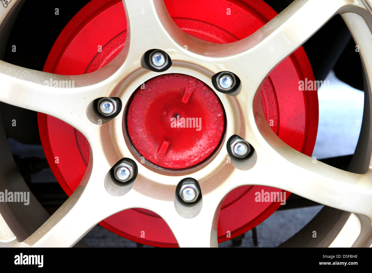 The Gold Alloy Wheel and Red Background. Stock Photo