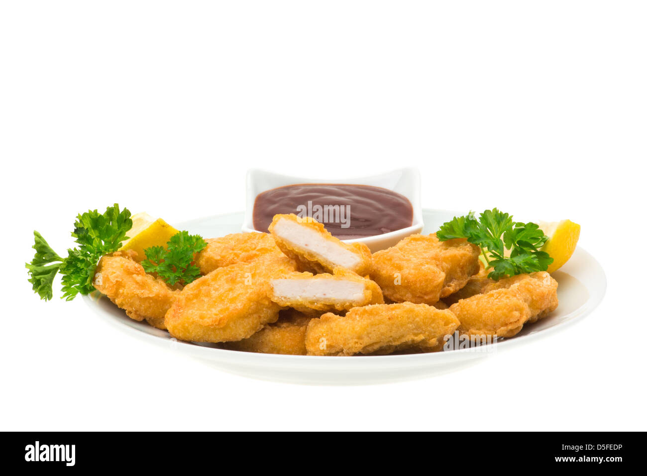 Chicken nuggets with lemon slices and a barbecue dip, served on a plate and ready to eat - white background Stock Photo