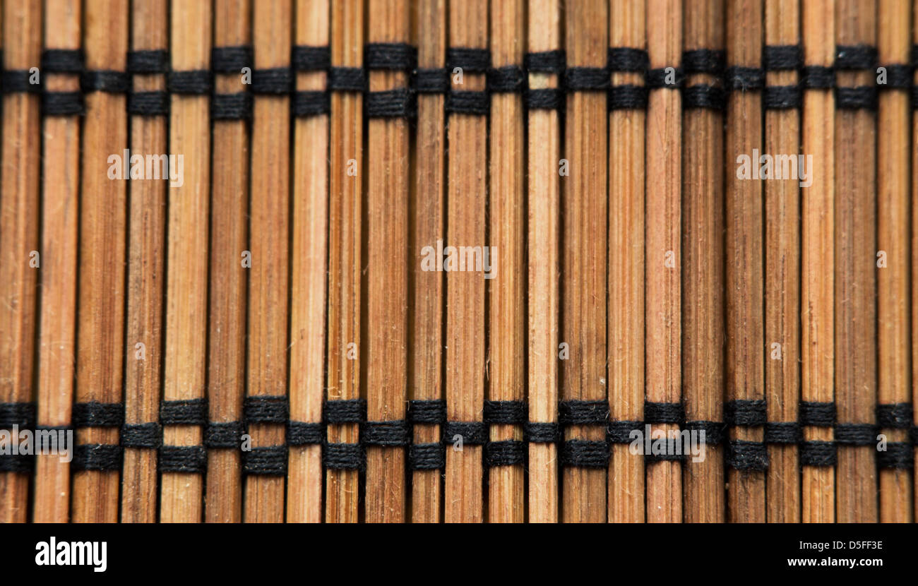 A close-up photograph of a wooden place mat in a Japanese style. The black stitching accentuates the borders Stock Photo