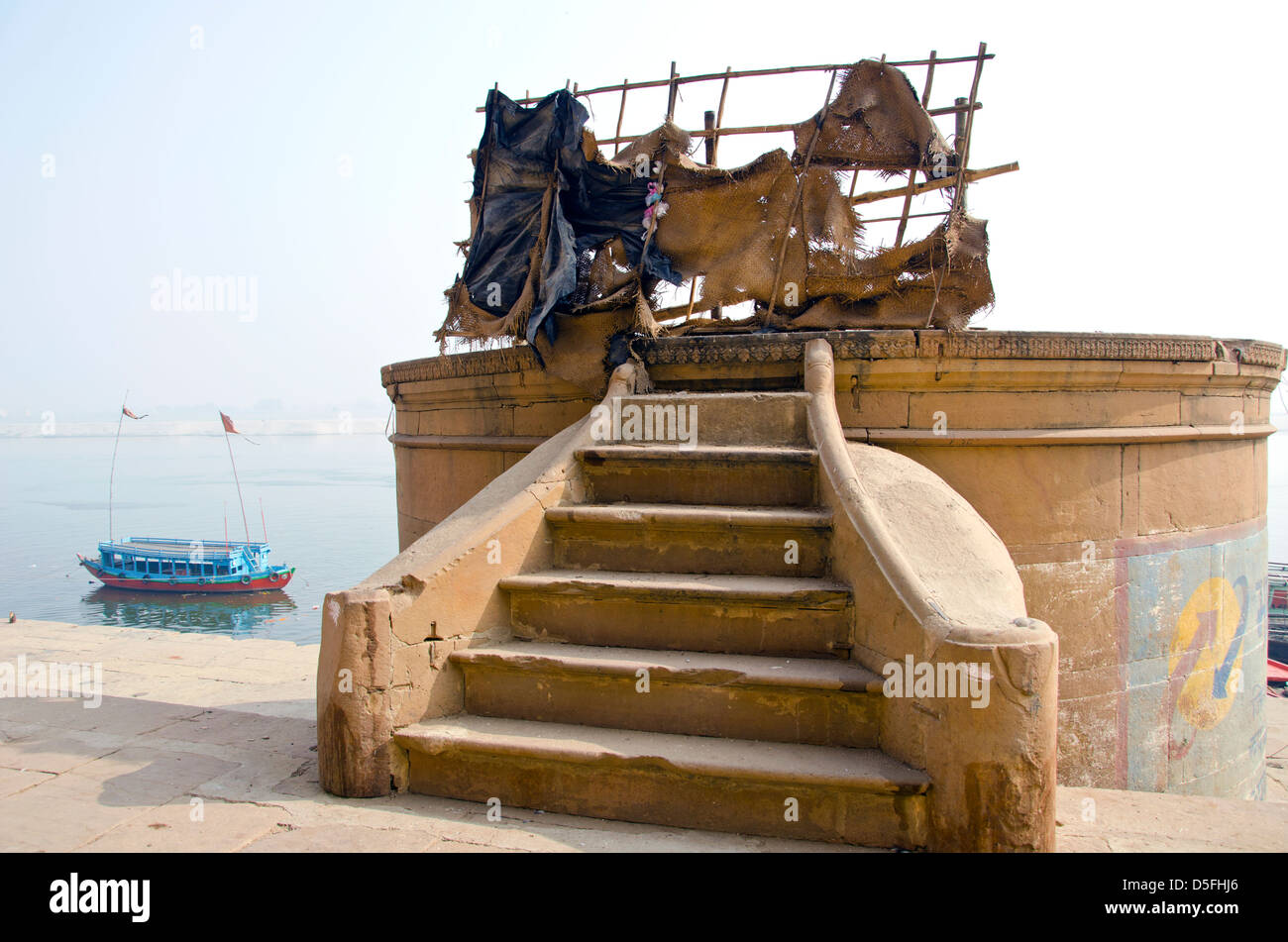 staircase on sacred Ganges river coast and boat in Varanasi, India Stock Photo