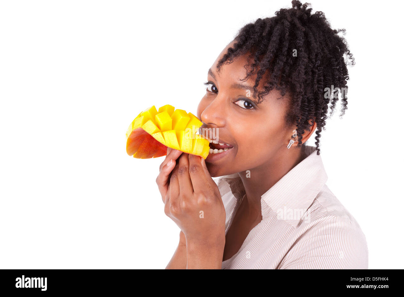 Young happy black / african american woman eating fresh mango isolated on white background Stock Photo