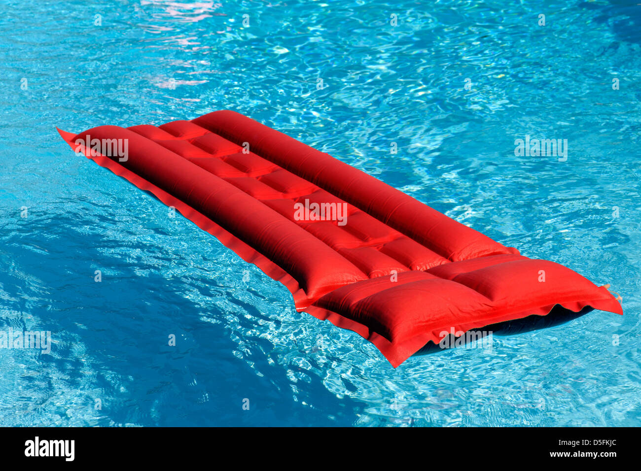 Red airbed floating in swimming pool Stock Photo