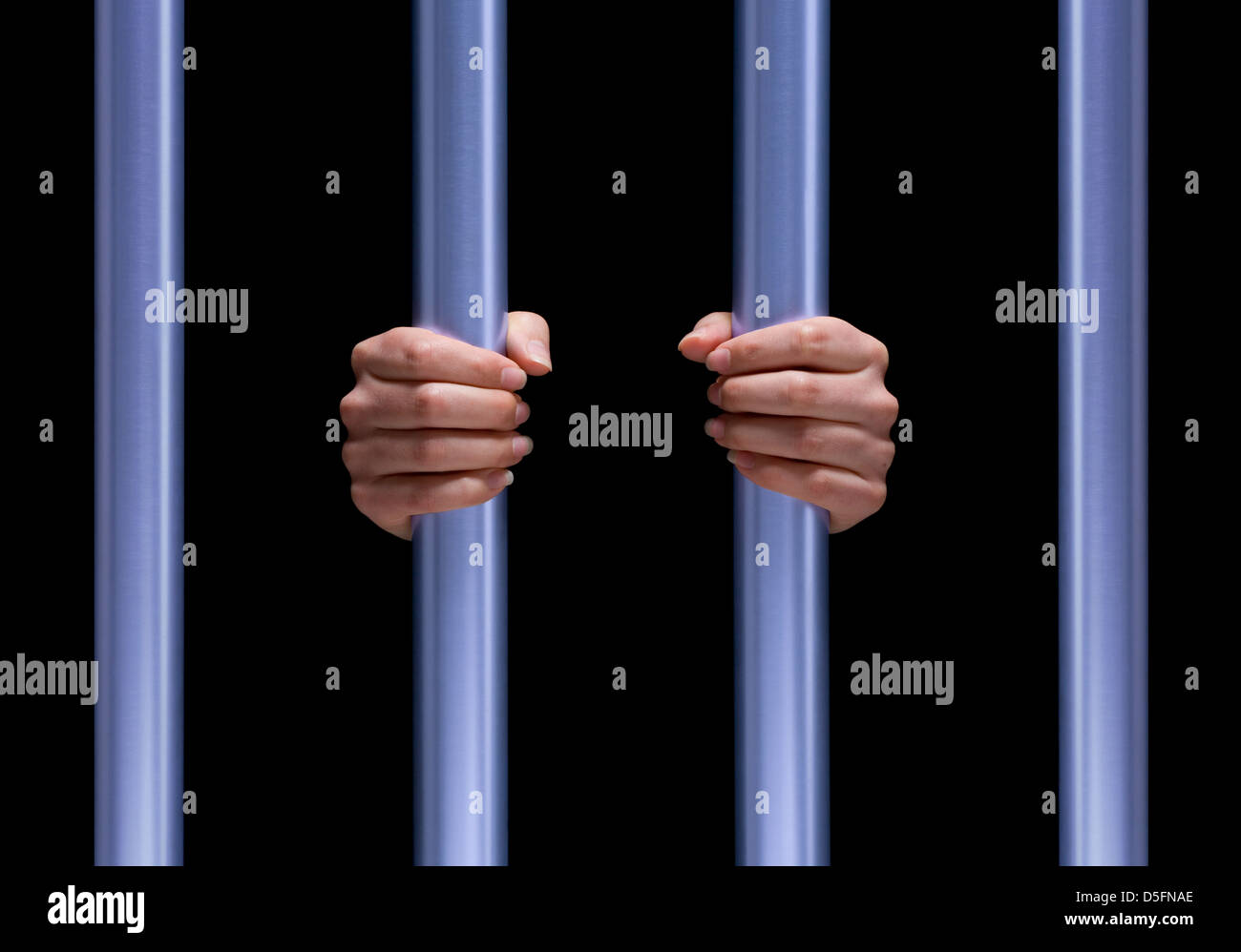 female prisoner with her hands clasping the bars of a jail cell Stock Photo