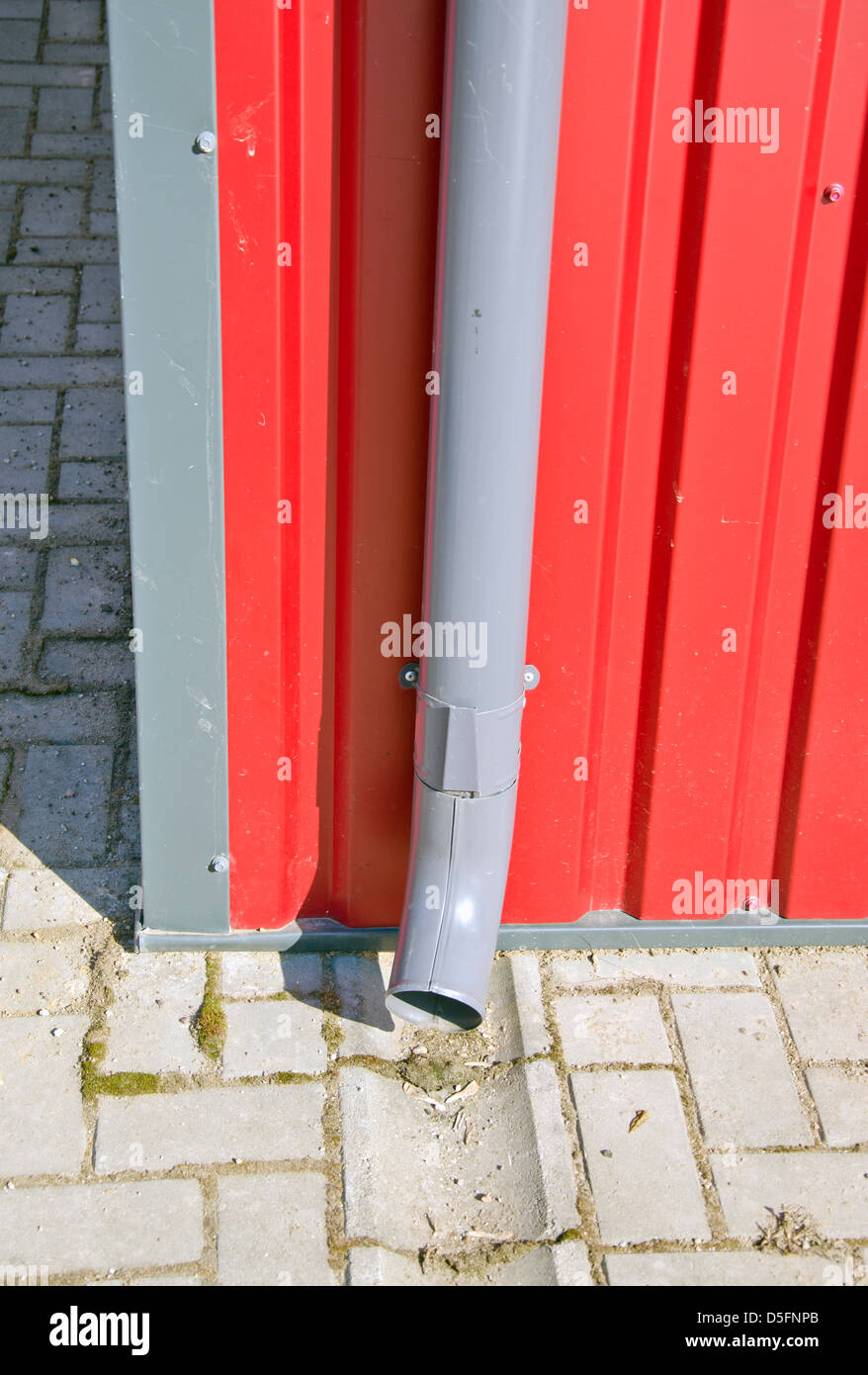 rain water drain gutter on new house red metal wall Stock Photo