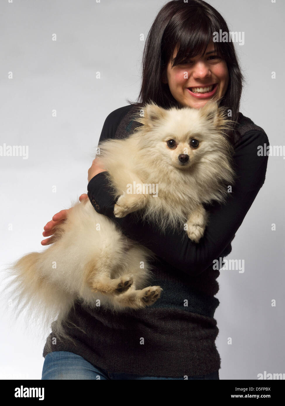Woman holding small white pomeranian dog Stock Photo