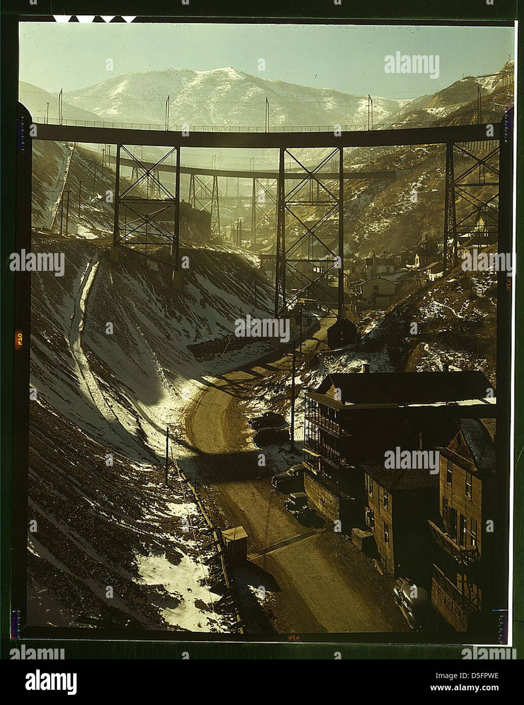 A 1940s color photograph of Carr Fork Canyon from the 'G' bridge, with views of the Bingham Copper Mine in Utah. The image showcases the mining landscape and industrial operations in the region. Stock Photo