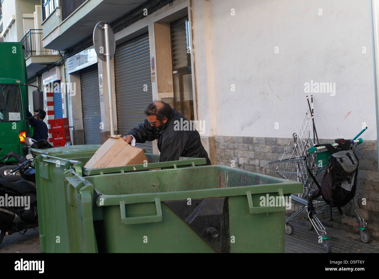 A jobless man pulls a trolley to carry the junk found on the bins. Stock Photo