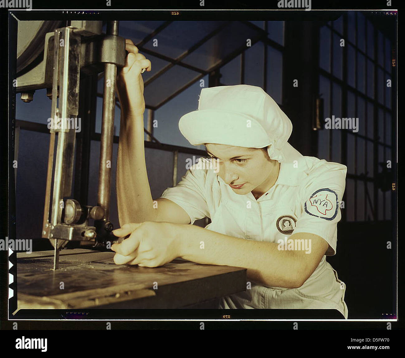 Women in white doctor Navy planes (motors) at the Naval Air Base, Corpus Christi, Texas. Mildred Webb, an NYA trainee at the base, is learning to operate a cutting machine in the Assembly and Repair Department. After about eight weeks as an apprentice s Stock Photo