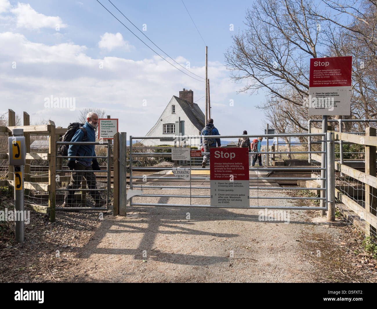 People walking across unmanned level crossing over a railway line at Glan-y-mor Elias near Llanfairfechan Conwy North Wales UK Stock Photo