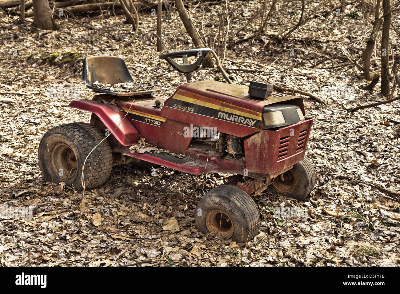 ride on lawn mower left in the woods rusting away Stock Photo
