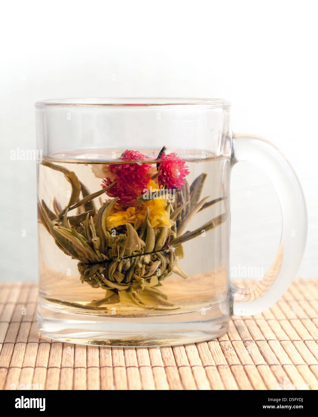 Green Chinese flower tea is brewed in the cup on bamboo carpet Stock Photo