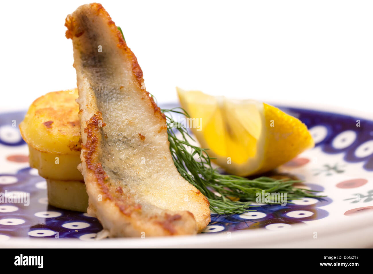 Perch filet with fried potatoes, lemon and dill in a blue plate Stock Photo