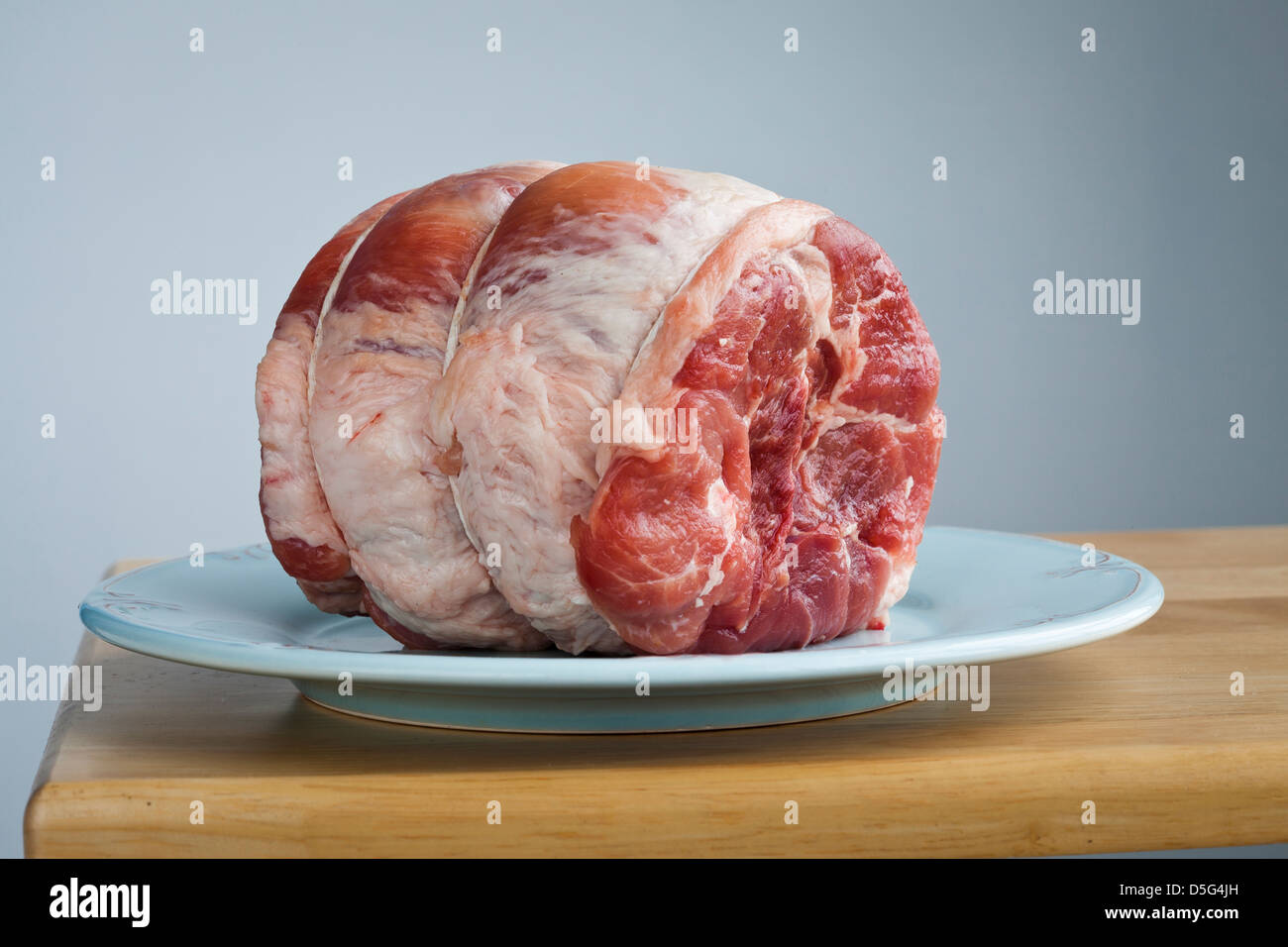 2.5 pound raw pork roast on a blue plate Stock Photo