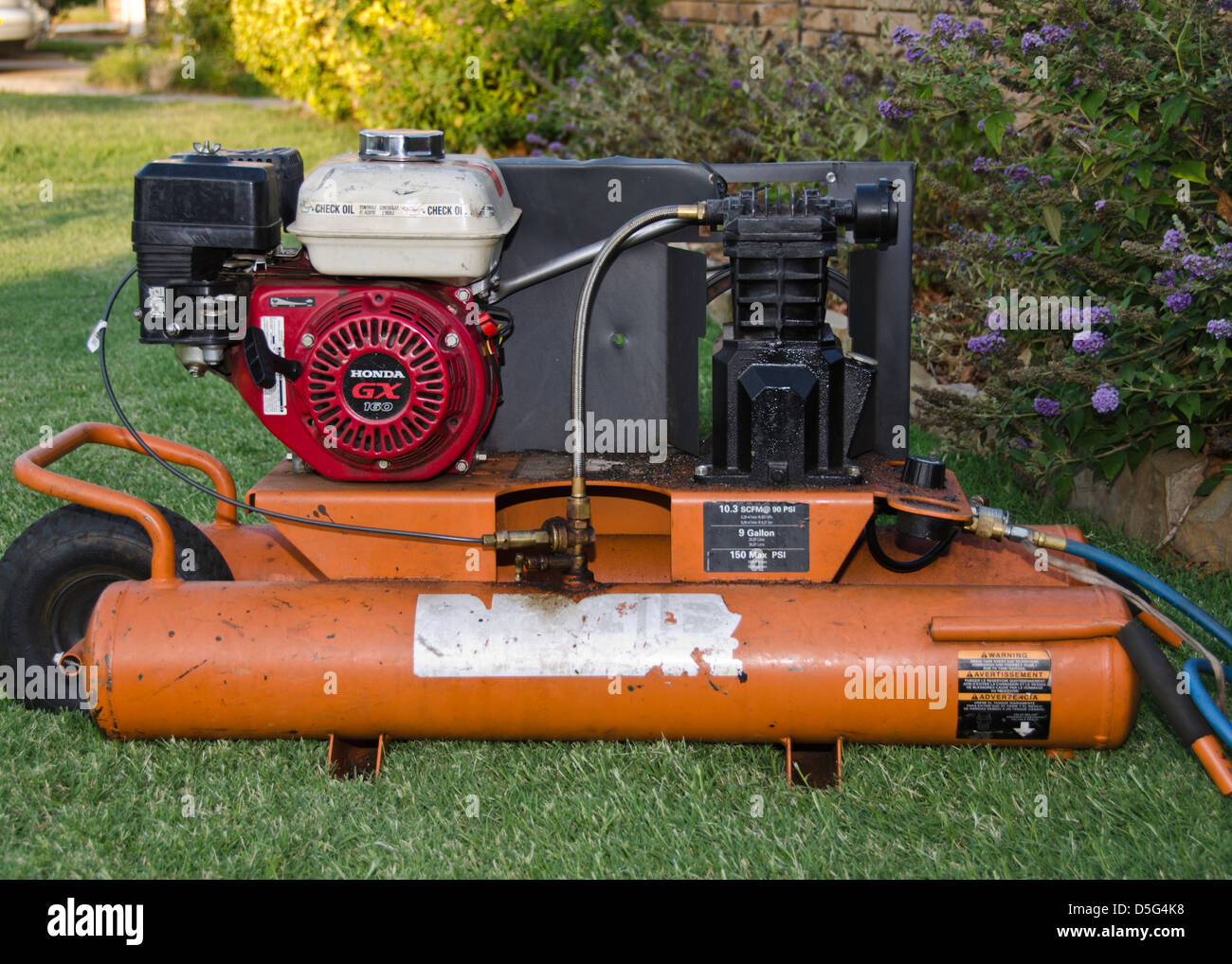 A Honda GX 160 engine, used as a roofer's nail gun compresser, sits on the  ground tin front of the house. Oklahoma, USA Stock Photo - Alamy