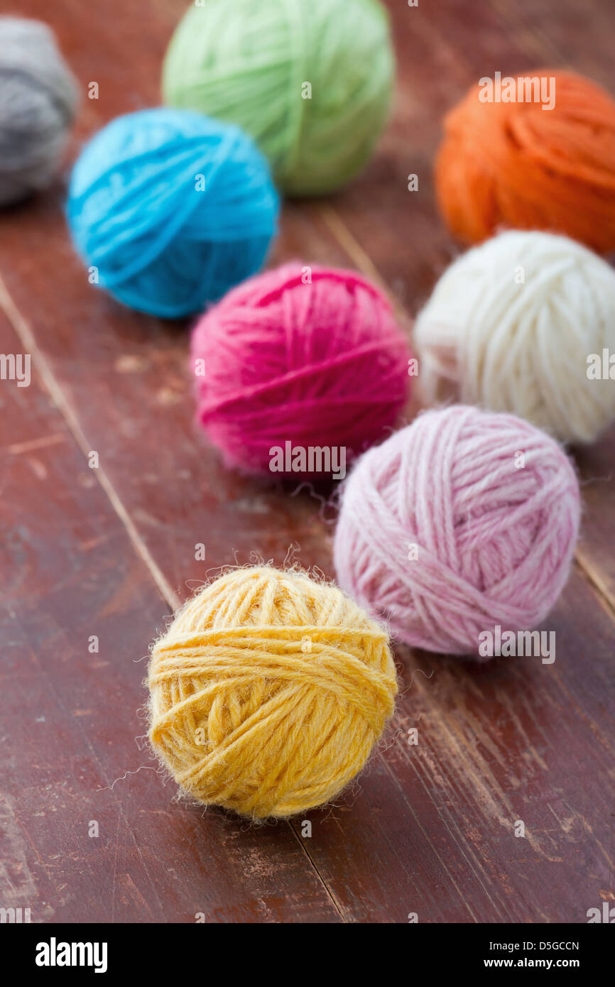 Colorful balls of woolen yarn on old vintage red wooden background Stock Photo