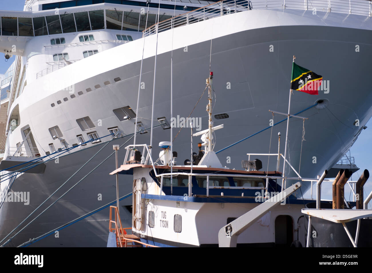 A huge cruise ship docked behind a tug in Basseterre, St Kitts, Caribbean region Stock Photo