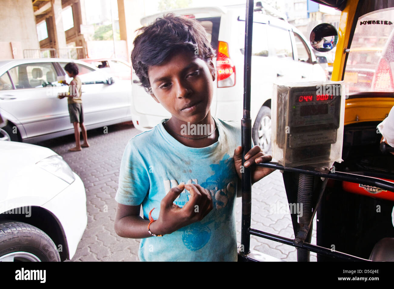 Indian boy begs for money from tuk tuk passengers in Mumbai traffic jam Stock Photo