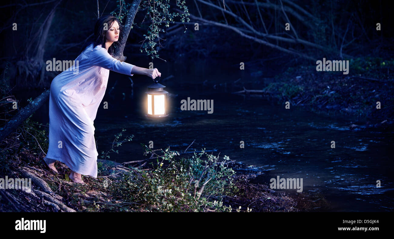 Woman with lantern over looking creek Stock Photo