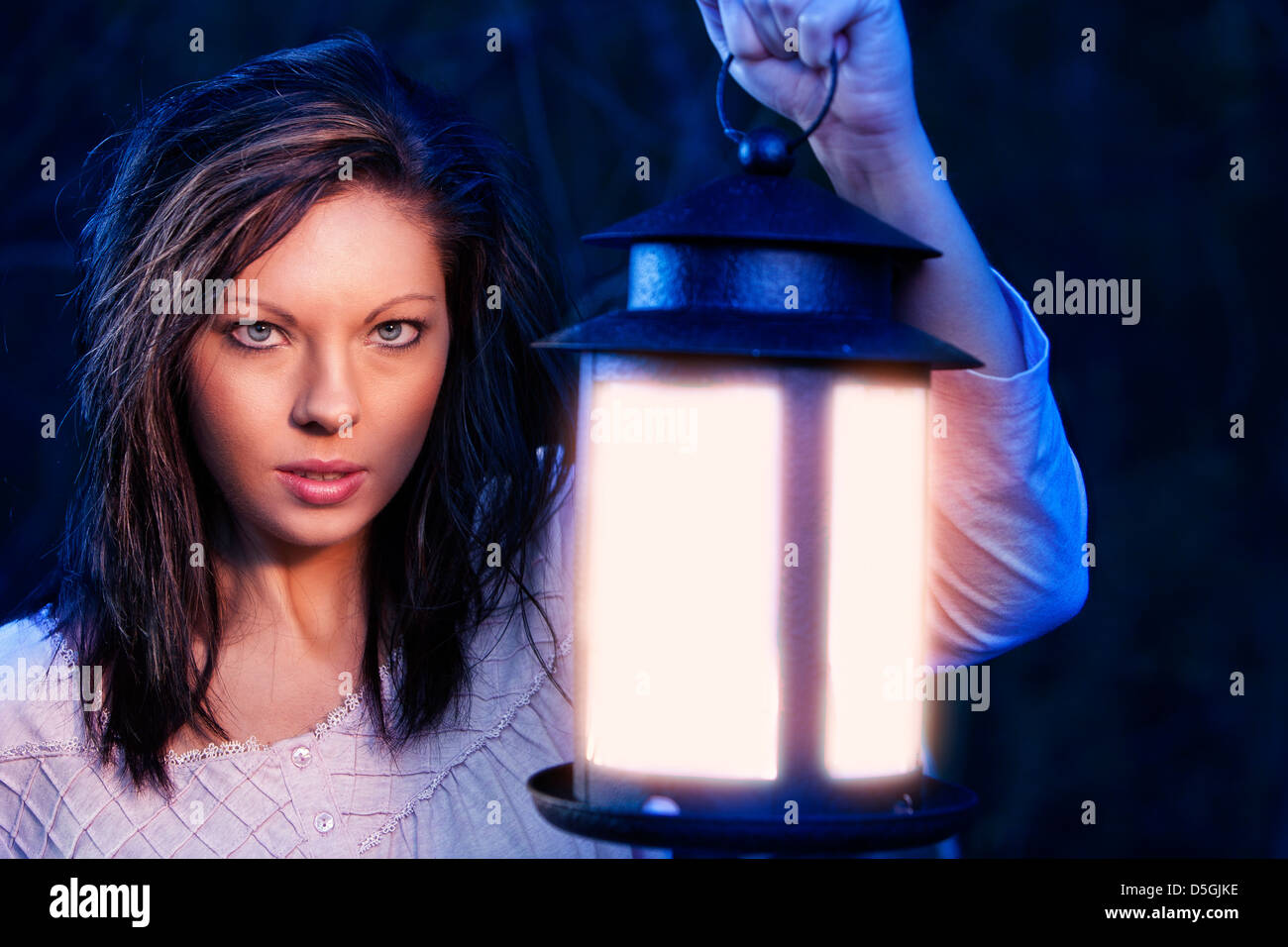 Woman with lantern in blue light Stock Photo