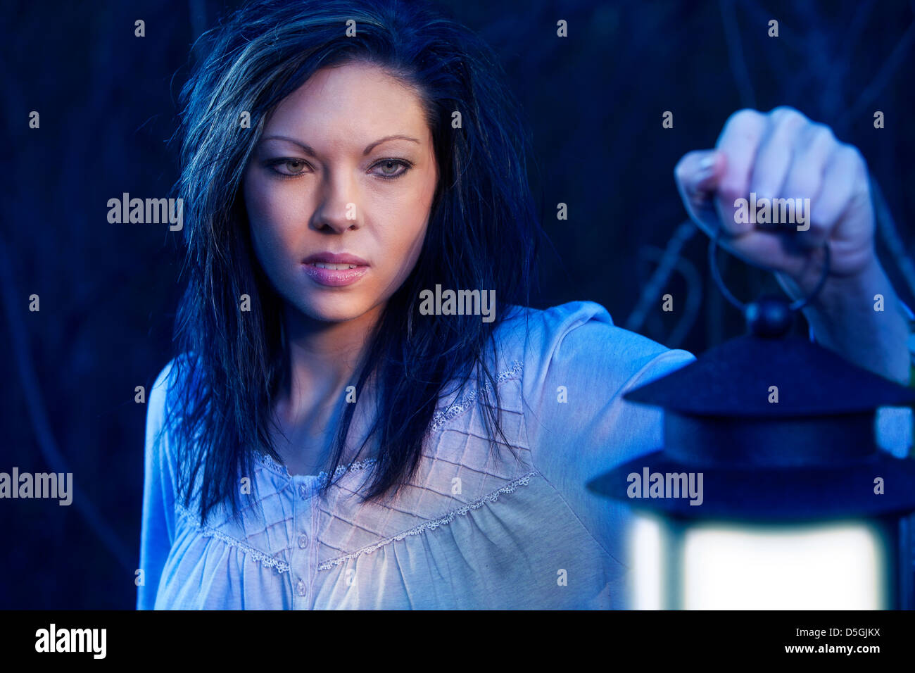Woman with lantern in blue light Stock Photo
