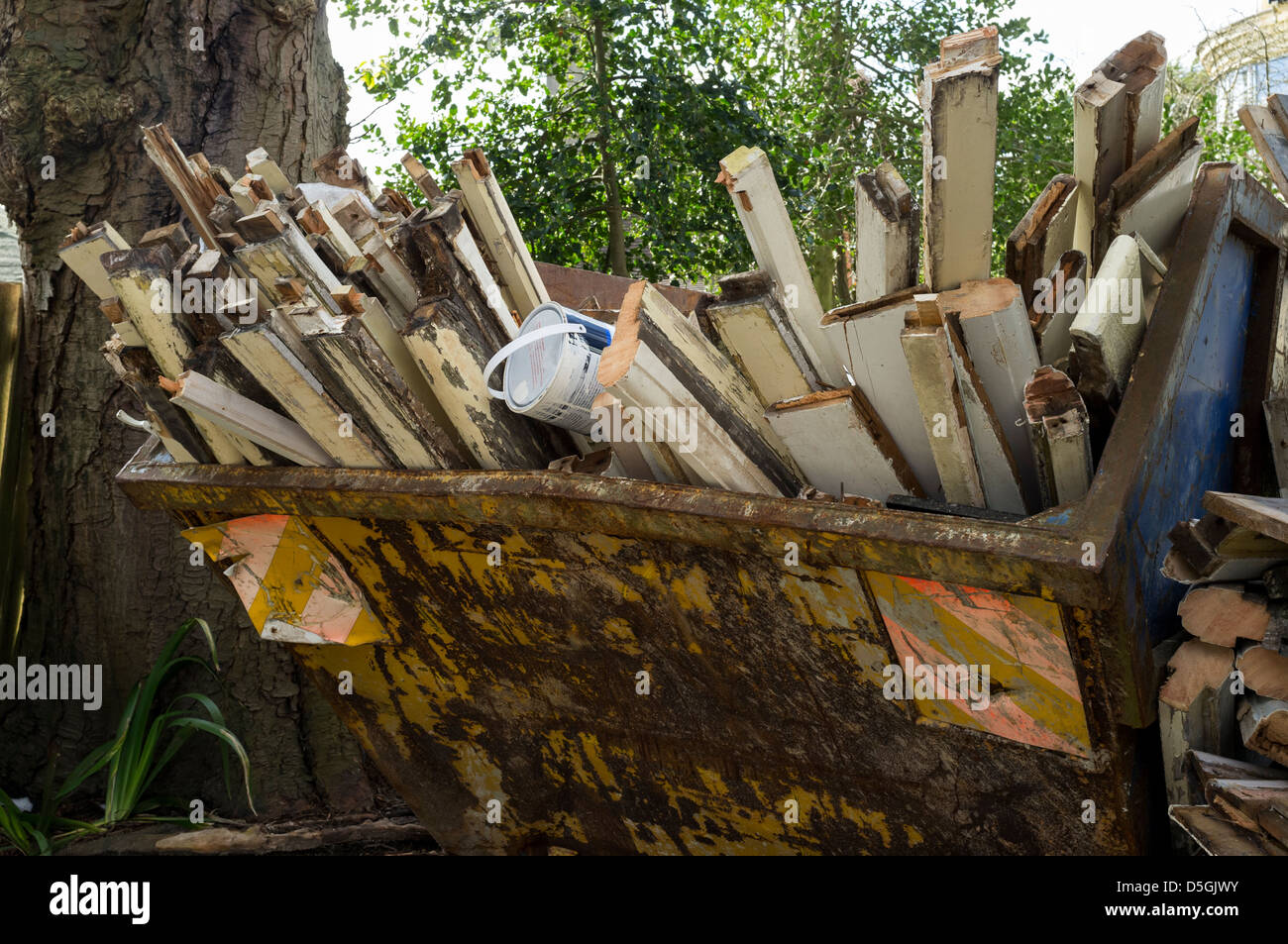 A full rubbish skip containing timber and paint cans Stock Photo Alamy