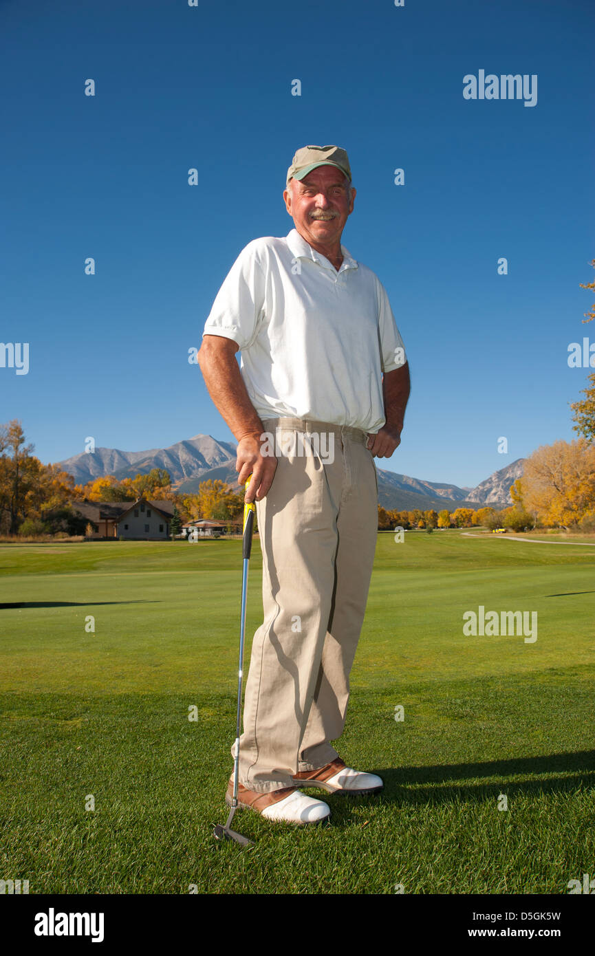 A male senior citizen is pleased with his golf game on a mountain golf course. Stock Photo