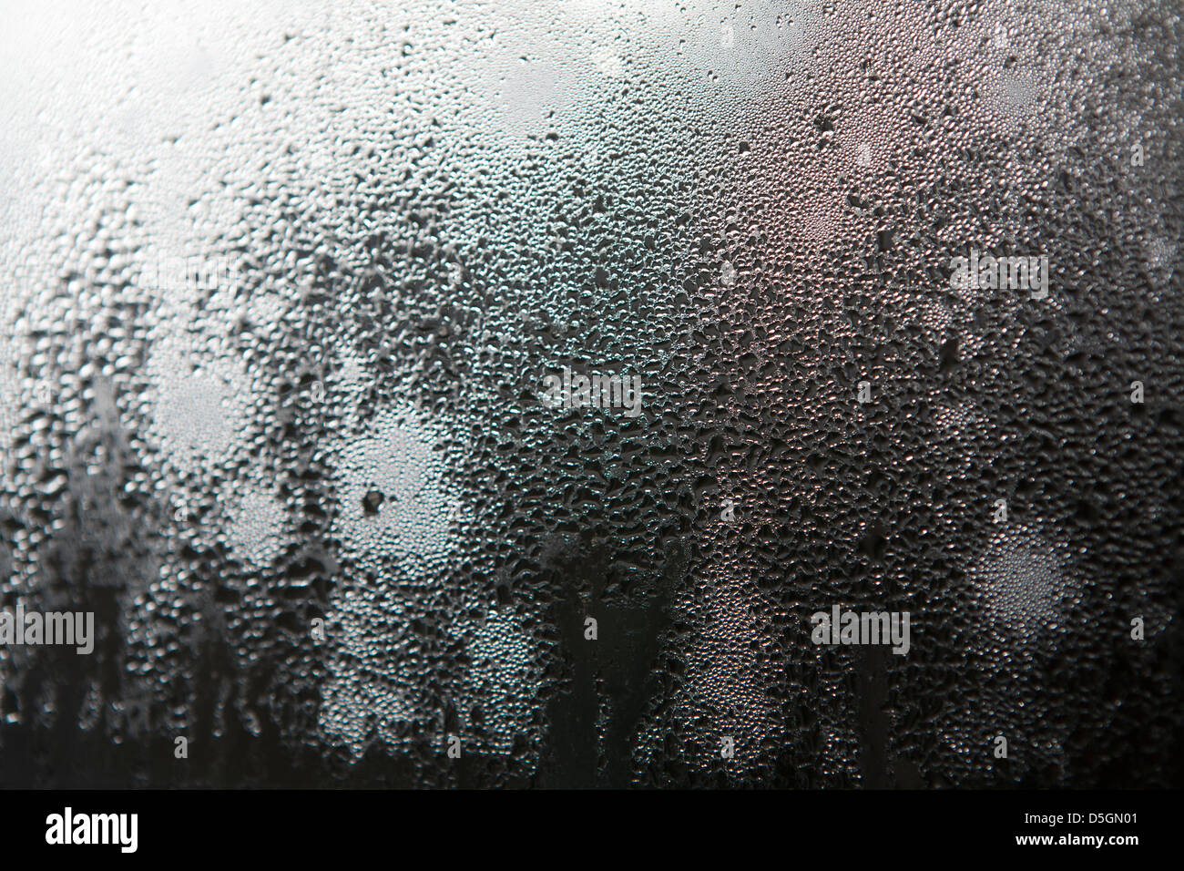 Close up of condensation droplets on a single glazed window pane in a small English cottage. Stock Photo