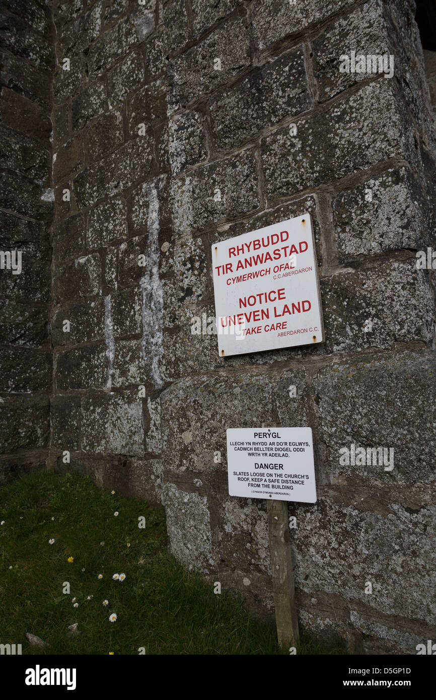 Aberdaron New Church in a state of disrepair, with warning signs relating to falling slates and uneven land. Stock Photo