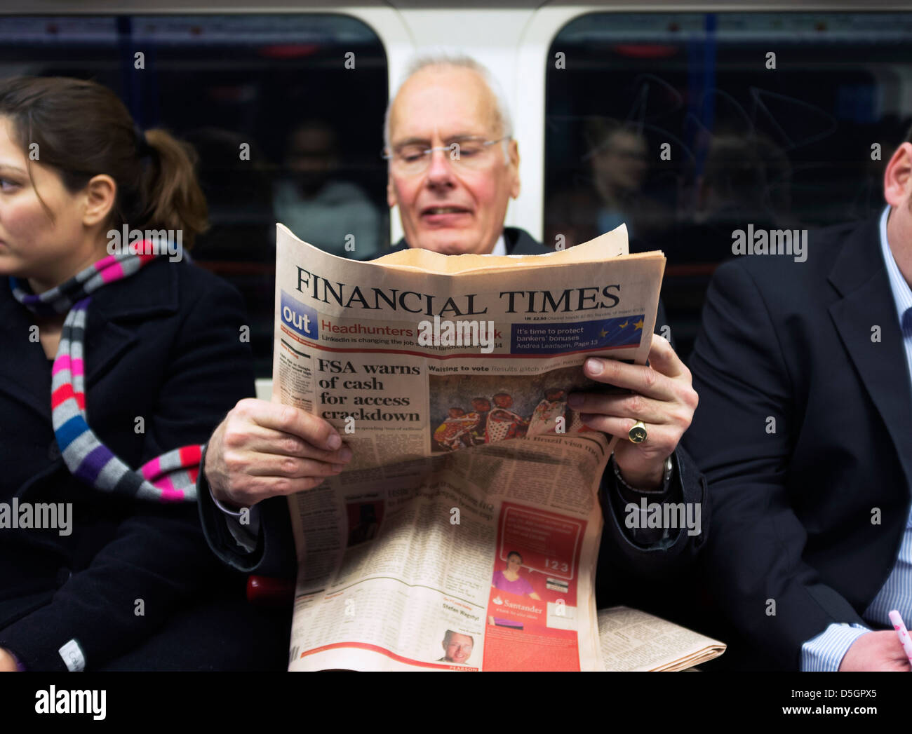 A man commuter reading the Financial Times on a tube train on London Underground transport system. Stock Photo