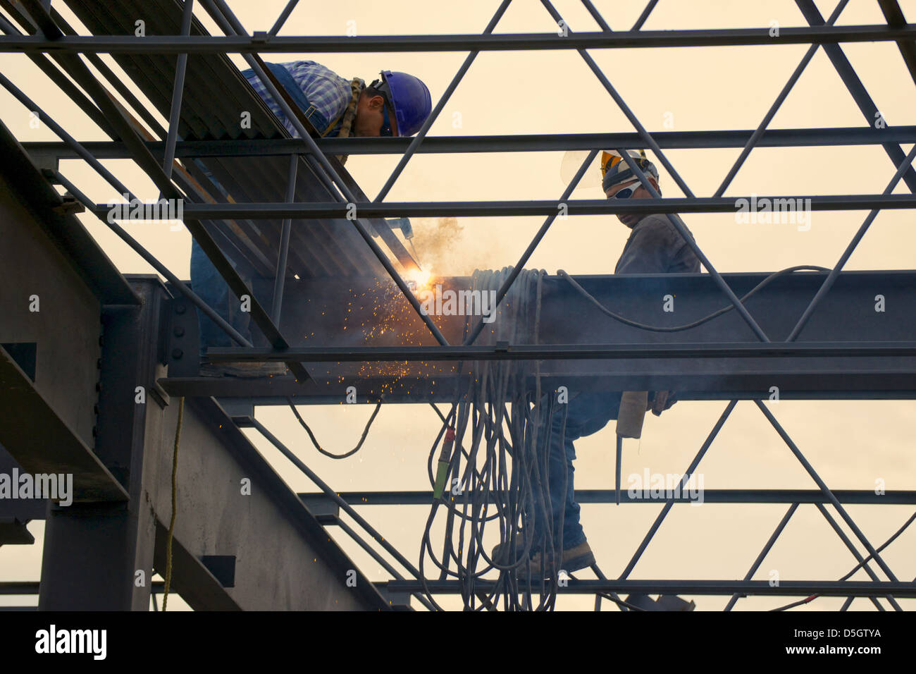Ironworkers welding the steel framework of a building. One welding one