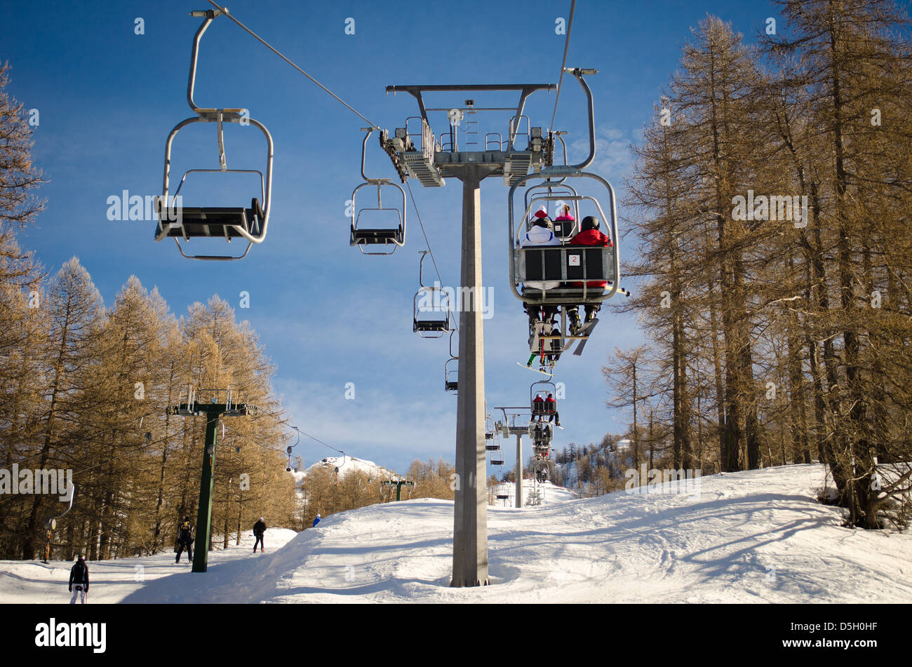 People and skiers on chairlift (aerial lift) and skilift in sunny day Stock Photo