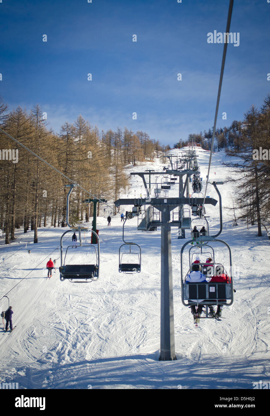 People and skiers on chairlift (aerial lift) and skilift in sunny day Stock Photo