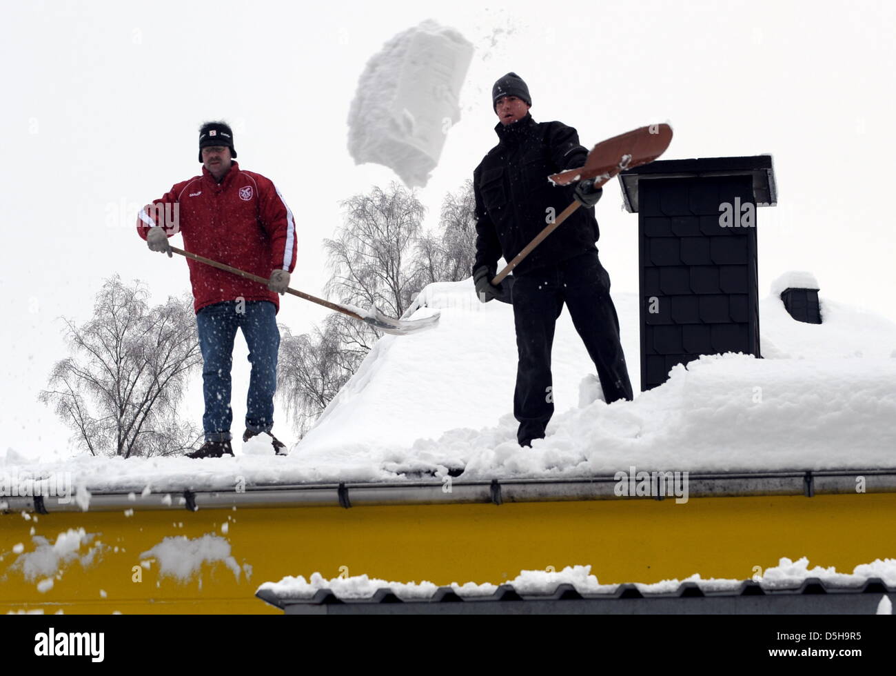 Staff members of a carpenter's shovel snow from the roof in WendenRothemuehle, Germany