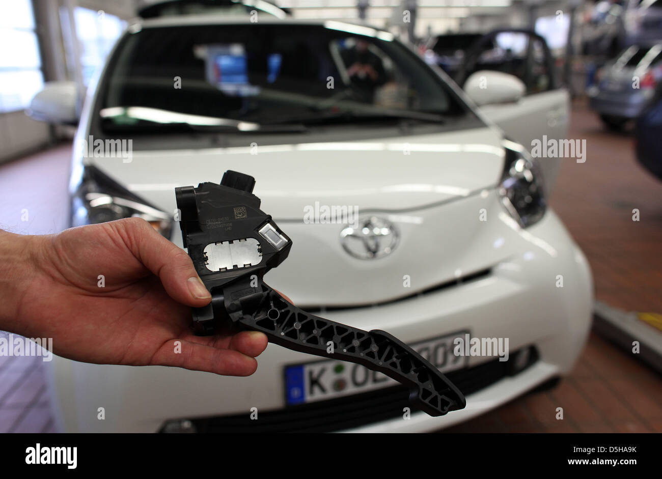 A mechanic of Toyota presents a throttle pedal of a Toyota iQ in Toyota garage in Cologne, Germany, 04 February 2010. A total of 215,796 cars are affected by Toyota's recall campaign due to locking throtel pedals, among them various years of construction of the models AYGO, iQ, Yaris, Auris, Corolla, Verso, Avensis and RAV4. Photo: OLIVER BERG Stock Photo