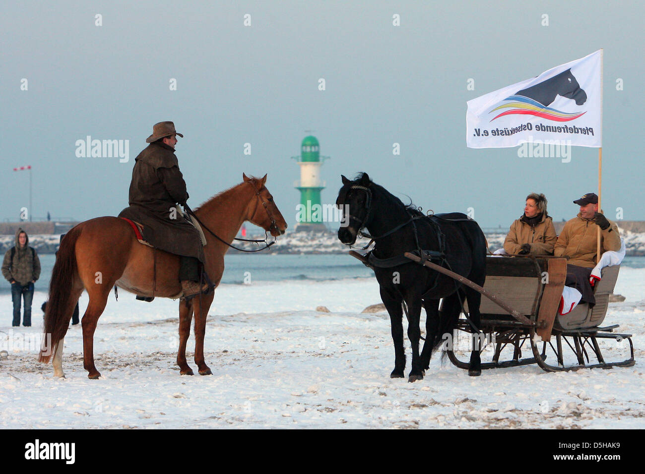 People on horses attend the 'Warnemuende Winter Fun' at the snowy Baltic Sea beach in Warnemuende, Germany, 05 February 2010. Beach fires, beach chairs and gluehwein craeated a pleasurable atmosphere. Photo: Bernd Wuestneck Stock Photo