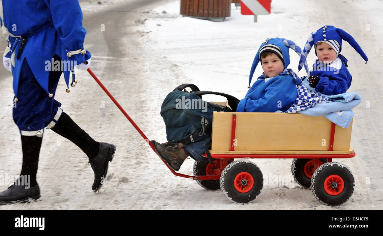 Linus and Paul sit in a hand cart which is pulled by their father during the traditional storming of the city hall in Staufen, Germany, 11 February 2010. The 'Schmotzige Dunschtig' ('Dirty Thursday') is the first highlight of the Swabian-Alemannic Carnival; on this day, jesters take over the city halls of many cities in Baden-Wuerttemberg. Photo: ROLF HAID Stock Photo