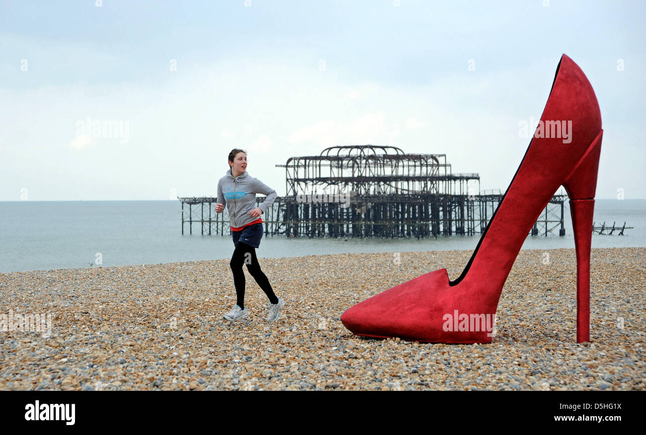 A giant red stiletto shoe caused a stir for early morning runners and passers by on Brighton seafront today when it appeared as part of Churchill Square Shopping Centre's If the Shoe Fits Event which is taking place over the next couple of days. Stock Photo