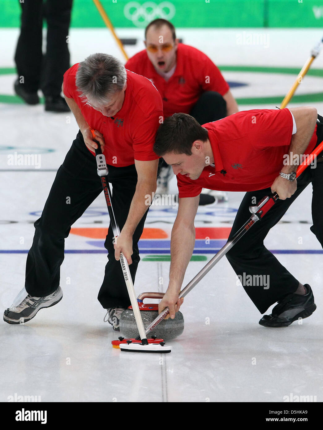 Holger Hoehne (C) of Germany releases his stone as Andreas Kempf (L) and Andy Lang guide it during Curling men's round robin session 3 at the Olympic Center during the Vancouver 2010 Olympic Games in Vancouver, Canada 17 February 2010. Germany's opponent was Sweden. Photo: Daniel Karmann  +++(c) dpa - Bildfunk+++ Stock Photo
