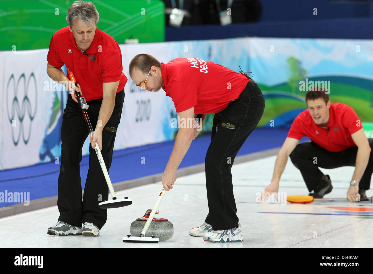 Skip Andy Lang (R) releases his stone as Andreas Kempf (L) and Holger Hoehne guide it during Curling men's round robin session 3 at the Olympic Center during the Vancouver 2010 Olympic Games in Vancouver, Canada 17 February 2010. Germany's opponent was Sweden. Photo: Daniel Karmann  +++(c) dpa - Bildfunk+++ Stock Photo