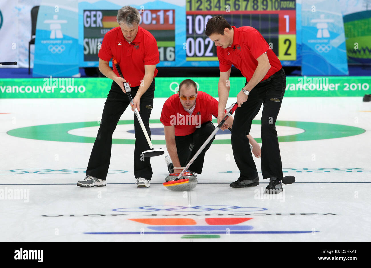 Holger Hoehne (C) of Germany releases his stone as Andreas Kempf (L) and Andy Lang guide it during Curling men's round robin session 3 at the Olympic Center during the Vancouver 2010 Olympic Games in Vancouver, Canada 17 February 2010. Germany's opponent was Sweden. Photo: Daniel Karmann Stock Photo