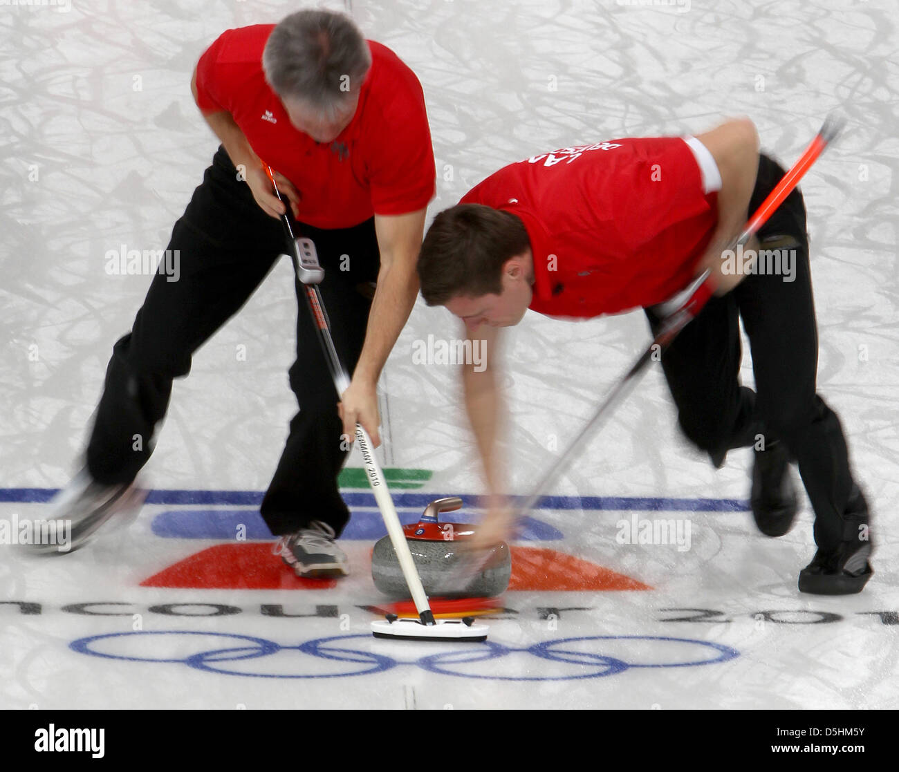 Andy Lang (L) of Germany and teammate Holger Hoehne sweep the ice to guide the stone during their curling men's round robin session 4 against Norway during the Vancouver 2010 Olympic Games at the Vancouver Olympic Center in Vancouver, Canada 18 February 2010. Photo: Daniel Karmann  +++(c) dpa - Bildfunk+++ Stock Photo