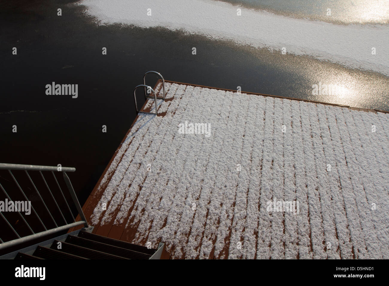 Snow covered Pontoon on frozen lake on sunny day Winter sun Stock Photo