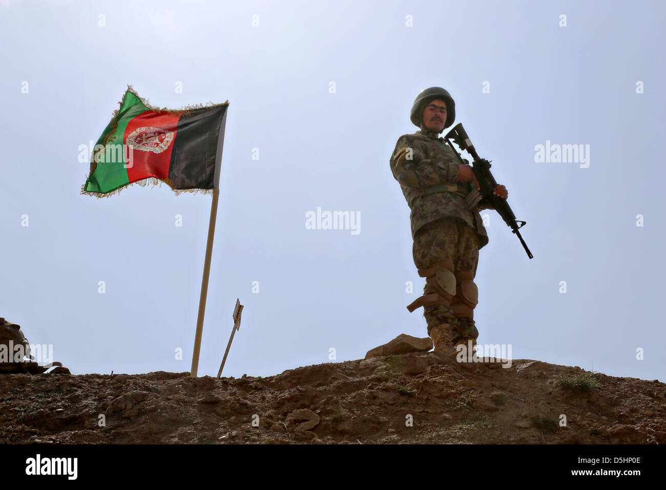 An Afghan National Army Special Forces soldier guards an Afghan flag at a weapons range March 18, 2013 in the Kabul district, Kabul province, Afghanistan Stock Photo