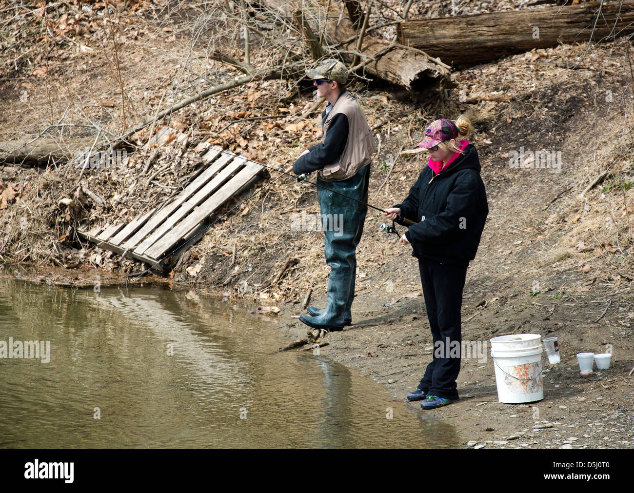 A young white caucasian couple fishing along a river. First day of trout season. Stock Photo