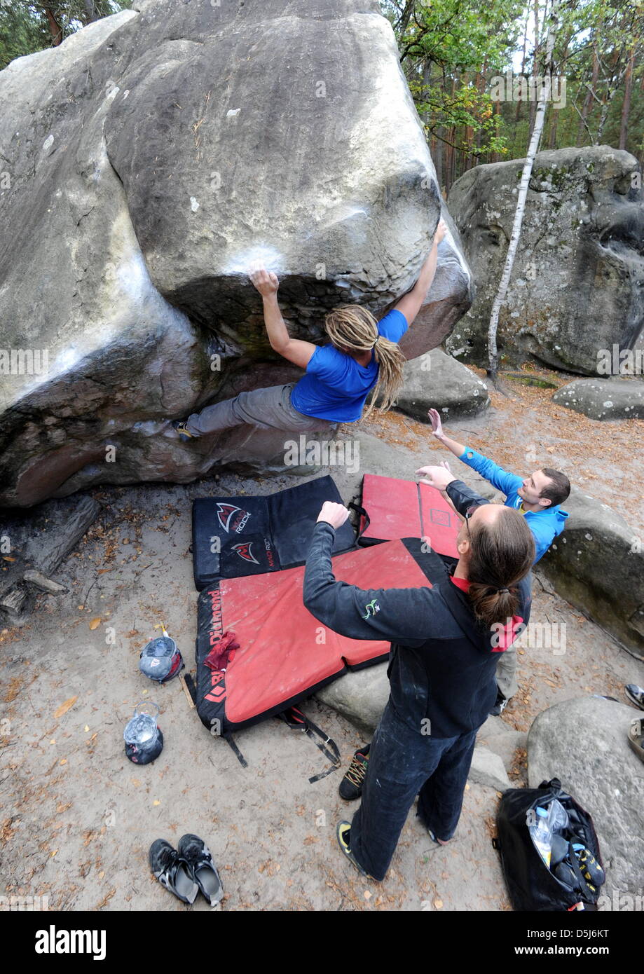 Der Boulderer Alexander Netz klettert am 02.10.2012 bei Fontainebleau in Frankreich im Bouldergebiet Roche aux Sabots an einem Felsblock empor während er von anderen Boulderern beobachtet wird. Fontainebleau zählt zu den größten und bekanntesten Bouldergebieten der Welt. Beim Bouldern klettert der Sportler auf Felsblöcke entlang einer definierten Linie ohne Sicherungsseil, dafür me Stock Photo