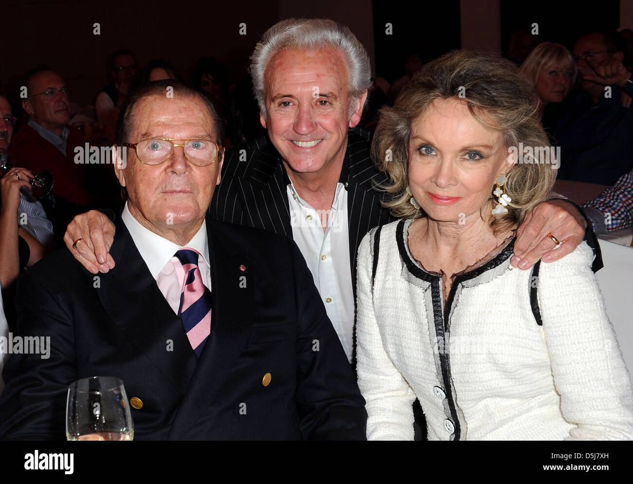 British actor Sir Roger Moore (l), his wife Kristina Tholstrup (r) and British singer Tony Christie (M) talk at the Get Together Party of the Hermes Eagles Golf cup at Nobilis Robinson Club in Belek, Turkey, 16 November 2012. Celebrities from sports, film and economy play for foundations such as the childrens emergency funds and the Beckenbauer foundation. Photo: Ursula Dueren Stock Photo