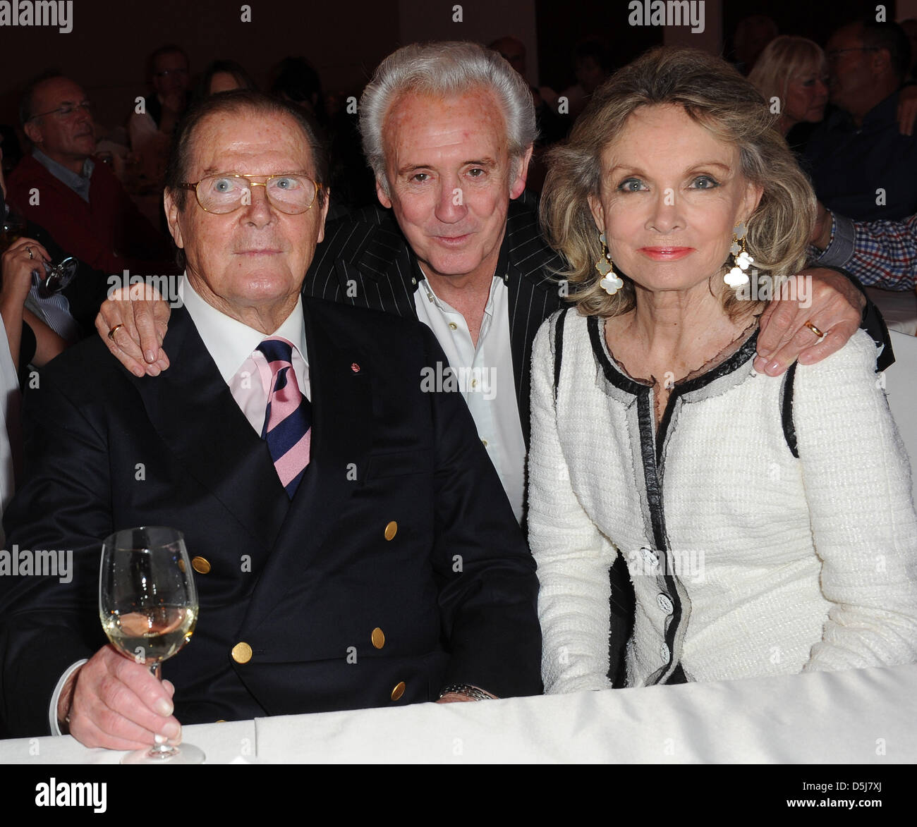 British actor Sir Roger Moore (l), his wife Kristina Tholstrup (r) and British singer Tony Christie (M) talk at the Get Together Party of the Hermes Eagles Golf cup at Nobilis Robinson Club in Belek, Turkey, 16 November 2012. Celebrities from sports, film and economy play for foundations such as the childrens emergency funds and the Beckenbauer foundation. Photo: Ursula Dueren Stock Photo