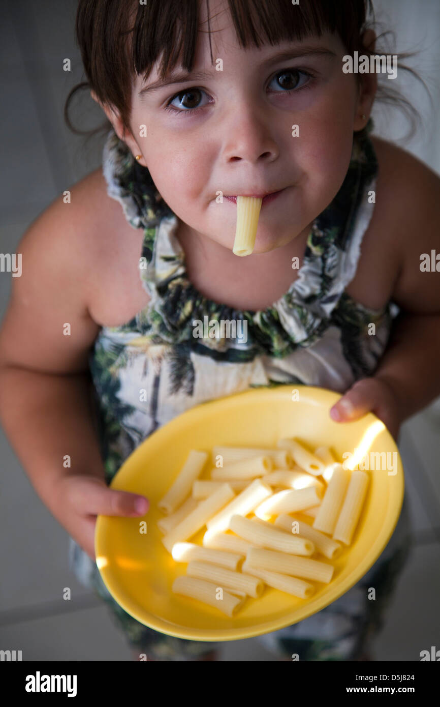 Girl Eating Plain Pasta with One Tube in Mouth Stock Photo